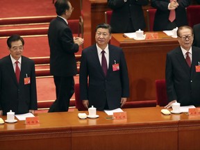 Chinese President Xi Jinping, center, and former Presidents Hu Jintao, left, and Jiang Zemin, right, stand at the beginning of the opening session of China's 19th Party Congress at the Great Hall of the People in Beijing, Wednesday, Oct. 18, 2017. (AP Photo/Mark Schiefelbein)