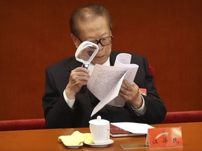 Former Chinese President Jiang Zemin uses a magnifying glass to read a work report during the opening session of China's 19th Party Congress at the Great Hall of the People in Beijing, Wednesday, Oct. 18, 2017. Chinese President Xi Jinping on Wednesday urged a reinvigorated Communist Party to take on a more forceful role in society and economic development to better address "grim" challenges facing the country as he opened a twice-a-decade national congress. (AP Photo/Mark Schiefelbein)