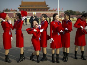 Hospitality staff members laugh as they stand on Tiananmen Square before the closing ceremony of China's 19th Party Congress at the Great Hall of the People in Beijing, Tuesday, Oct. 24, 2017. The ruling Communist Party on Tuesday formally lifted Xi Jinping's status to China's most powerful ruler in decades, setting the stage for the authoritarian leader to tighten his grip over the country while pursuing an increasingly muscular foreign policy and military expansion. (AP Photo/Mark Schiefelbein)
