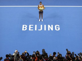 Photographers take photos as Caroline Garcia of France poses with the winner's trophy after beating Simona Halep of Romania in their women's singles championship match in the China Open tennis tournament at the Diamond Court in Beijing, Sunday, Oct. 8, 2017. (AP Photo/Mark Schiefelbein)
