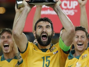 FILE - In this Jan. 31, 2015 file photo, Australia's Mile Jedinak holds the trophy aloft as he celebrates with his teammates after their AFC Asian Cup final soccer match win over South Korea in Sydney, Australia. Skipper Mile Jedinak has been recalled to Australia's squad for the first time since June to prepare for next month's World Cup intercontinental playoff against Honduras. (AP Photo/Quentin Jones, File)