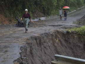 Neighbors walk under the rain past a washed out road in Alajuelita on the outskirts of San Jose, Costa Rica, Thursday, Oct. 5, 2017. Tropical Storm Nate formed off the coast of Nicaragua on Thursday and was being blamed for at least 17 deaths in Central America as it spun north toward a potential landfall on the U.S. Gulf Coast as a hurricane over the weekend. (AP Photo/Moises Castillo)
