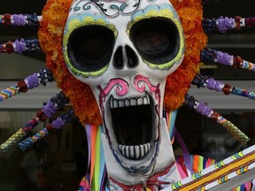 A man wearing a costume of Mexico's iconic "Catrina," in honor of Day of the Dead festivities, poses for photos at the Hermanos Rodriguez racetrack in Mexico City, Thursday, Oct. 26, 2017. The Mexican Grand Prix is set for Sunday. (AP Photo/Marco Ugarte)