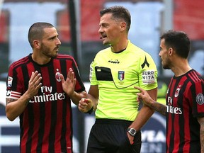 AC Milan defender Leonardo Bonucci, left, speaks with referee Piero Giacomelli, center, after receiving a red card during a Serie A soccer match between AC Milan and Genoa, at the Giuseppe Meazza stadium in Milan, Italy, Sunday, Oct. 22, 2017. Bonucci was sent off in the first half of Milan's 0-0 draw at home with Genoa on Sunday for elbowing a defender in the head as he jostled for position on a free kick.  (Matteo Bazzi/ANSA via AP)