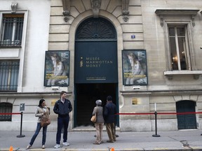 People wait outside the Marmottan museum in Paris, Tuesday, Oct.10, 2017. A painting exhibited in the museum called Called "La Cueillette des Bois," or "Picking Peas", by impressionist master Camille Pissarro that was looted by the Vichy regime during World War II is at the center of a legal battle in Paris. (AP Photo/Christophe Ena)