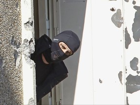 FILE - In this March 23, 2014 file photo, a masked police officer searches for clues at terrorist Mohamed Merah's apartment building in Toulouse, southwestern France. Once nicknamed Bin Laden in the French housing project where he grew up, the violence-prone ex-delinquent Abdelkader Merah, brother of Mohamed Merah, now says he is a peaceful Muslim and has displayed calm, wit and knowledge at his terror trial in Paris. (AP Photo/Remy de la Mauviniere, File)