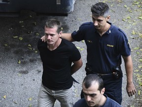A Russian man identified as Alexander Vinnik, left, is escorted by police officers as he arrives to the courthouse at the northern Greek city of Thessaloniki on Wednesday, Oct. 4, 2017. The Greek court will announce Wednesday about the extradition of the Russian cybercrime suspect Vinnik, who is wanted in the United States in a $4 billion bitcoin fraud case. (AP Photo/Giannis Papanikos)