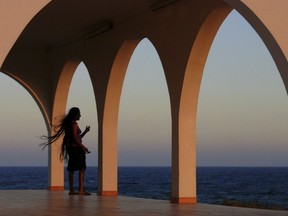 FILE - In this Saturday, July 6, 2013, file photo a woman walks outside the Ayia Thekli (Saint Thekla) Christian orthodox church near Ayia Napa resort in the southeast of the island of Cyprus. Couples who marry in civil ceremonies have been banned from taking wedding photos outside places of worship in a Cyprus region known for hosting destination weddings, a senior Orthodox Christian cleric announced Friday, Oct. 20, 2017. (AP Photo/Petros Karadjias, File)