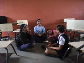 In this Friday, Oct. 13, 2017 photo, youths chat at the Ramon Marin Sola Elementary School, which opened its doors as a daytime community center after the passing of Hurricane Maria in Guaynabo, Puerto Rico. Children have been living in campus-turned-shelters in western Puerto Rico since Hurricane Maria flooded their homes, trying to pass the time while their families wait for help to replace the homes they lost in the storm. (AP Photo/Carlos Giusti)