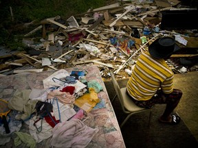 Efrain Diaz Figueroa spends the afternoon sitting on a chair next to the remains of the house of his sister destroyed by Hurricane Maria in San Juan, Puerto Rico, Monday, Oct. 9, 2017. Figueroa, who was visiting for a month at her sister Eneida's house when the Hurricane Maria hit the area, also lost her home in the Arroyo community. He waits for a relative to come from Boston and take him to Boston. He says that he is 70 years old and all his life working can't continue in these conditions in Puerto Rico. (AP Photo/Ramon Espinosa)