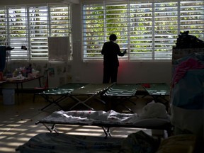 In this Thursday, Oct. 12, 2017 photo, a teenager left homeless by Hurricane Maria looks out the window of the school-turned-shelter where he's living in Toa Baja, Puerto Rico. Many schools on the island are functioning as temporary shelters for those affected by Hurricane, delaying student's education. (AP Photo/Ramon Espinosa)