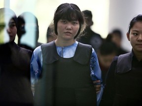 Vietnamese Doan Thi Huong, center, is escorted by police officers as she arrives for a court hearing at Shah Alam court house in Shah Alam, outside Kuala Lumpur, Malaysia, Thursday, Oct. 12, 2017. Security camera videos showed Wednesday Kim Jong Nam, the estranged half brother of North Korea's leader, being attacked at a Malaysian airport and the two suspects, including Doan, hurrying away afterward have been presented at their murder trial. (AP Photo/Sadiq Asyraf)