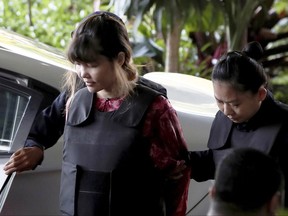 Vietnamese Doan Thi Huong, left, is escorted by police as she arrives for court hearing at Shah Alam court house in Shah Alam, outside Kuala Lumpur, Malaysia Thursday, Oct. 5, 2017. Doan and Siti Aisyah of Indonesia have pleaded not guilty to killing Kim Jong Nam on Feb. 13 at a crowded Kuala Lumpur airport terminal. They are accused of wiping VX on Kim's face in an assassination widely thought to have been orchestrated by North Korean leader Kim Jong Un. (AP Photo/Sadiq Asyraf)