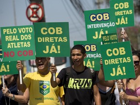 People protest holding signs with the message that reads in Portuguese: "COB, Elections now!," outside the headquarters of the COB, or Brazil Olympic Committee, in Rio de Janeiro, Brazil, Wednesday, Oct. 11, 2017. The COB called an extraordinary session where it is expected to discuss the arrest of its former president Carlos Nuzman, who was arrested last week in an investigation into a vote-buying scheme to win the rights to host the 2016 Olympics. (AP Photo/Silvia Izquierdo)