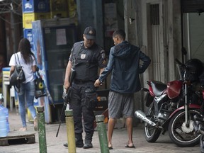 A police officer searches a resident at the Rocinha slum, in Rio de Janeiro, Brazil Tuesday, Oct. 24, 2017. Brazilian military police say officers killed a Spanish tourist when the vehicle she was traveling in came under fire after ignoring a police checkpoint. A military police statement says the incident followed a firefight between police officers and suspected drug traffickers early Monday in Rocinha, one of Brazil's largest slums. (AP Photo/Silvia Izquierdo)
