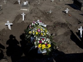 In this July 6, 2017 photo, shadows are cast on the burial site and coffin containing the remains of 10-year-old Vanessa dos Santos, in Rio de Janeiro, Brazil. As is common in crimes that happen in areas controlled by drug gangs, investigators are not always able or willing to risk their lives and examine the crime scene. To this day, police have not yet determined the origin of the bullet that killed Vanessa, who live and died in the Line complex of slums. (AP Photo/Silvia Izquierdo)