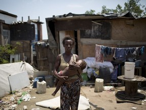 In this Oct. 20, 2017 photo, Simone Batista holds her 1-year-old Arthur outside her shack in the Jardim Gramacho slum of Rio de Janeiro, Brazil, one year after she was cut from the "Bolsa Familia" government subsidy program for low-income people. "Every day is a struggle to survive," said the 40-year-old. (AP Photo/Silvia Izquierdo)