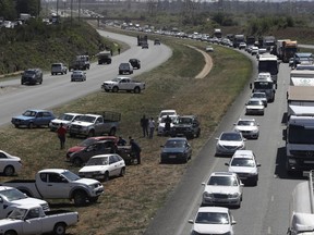 Vehicles blockade a freeway between Johannesburg and Vereeniging, South Africa, in protest against the recent murder of farmers, Monday, Oct 30 2017.  Traffic was bought to a standstill on highways leading from farming areas to Cape Town, Pretoria and Johannesburg, as white farmers protest in what they call the Black Monday protest against the high rate of murders of farmer workers.  (AP Photo/Themba Hadebe)