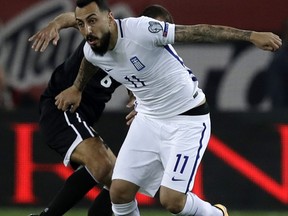 Greece's Kostas Mitroglou, front, controls the ball as Gibraltar's Roy Chipolina tries to stop him during the World Cup Group H qualifying soccer match between Greece and Gibraltar at Georgios Karaskaikis stadium in Piraeus port, near Athens, on Tuesday, Oct. 10, 2017. (AP Photo/Thanassis Stavrakis)