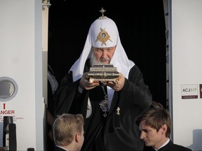 The head of the Russian Orthodox Church Patriarch Kirill holds a box containing holy remains as he comes out of the airplane before meeting Patriarch of Romanian Orthodox Church Daniel in Bucharest, Romania, Thursday, Oct. 26, 2017. The patriarch arrives in Romania on the first visit by the head of the powerful Russian church since communism ended. (AP Photo/Vadim Ghirda)