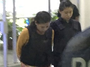 Indonesian Siti Aisyah, left, escorted by police, arrives for court hearing at Shah Alam court house in Shah Alam, Malaysia, Wednesday, Oct. 4, 2017. Aisyah and Doan Thi Huong of Vietnam pleaded not guilty on Monday, the trial's first day, to killing the estranged half brother of North Korea's leader on Feb. 13 at a crowded Kuala Lumpur airport terminal. They are accused of wiping VX on Kim Jong Nam's face in an assassination widely thought to have been orchestrated by North Korean leader Kim Jong Un. (AP Photo/Vincent Thian)
