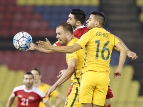 Australia's Aziz Behich, right, and his teammate Matthew Jurman, center, fight for control of the ball with Syria's Omar Alsoma during the 2018 World Cup qualifying football match between Syria and Australia at the Hang Jebat Stadium in Melaka, Malaysia, Thursday, Oct. 5, 2017. (AP Photo/Vincent Thian)