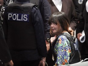 Vietnamese Doan Thi Huong, right, is escorted by police at Kuala Lumpur International Airport in Sepang, Malaysia, Tuesday, Oct. 24, 2017. The two women accused of killing Kim Jong Nam, the North Korean leader's half brother, toured the Malaysian airport Tuesday as participants in their murder trial visited the scene of the attack. (AP Photo/Sadiq Asyraf)