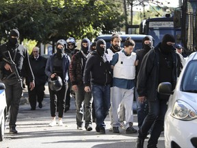 Greek policemen in plain clothes escort suspects to a prosecutor's office in Athens, Sunday, Oct. 29, 2017. Greek police arrested a 29-year-old suspect Saturday in a bomb attack last May on one of the country's former prime ministers. (AP Photo)