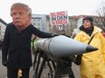 An activist with a mask of U.S. President Donald Trump marches with a model of a nuclear rocket during a demonstration against nuclear weapons on November 18, 2017 in Berlin, Germany.