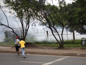 People run for safety on main Uhuru Highway as police fire tear gas Friday, Nov. 17, 2017. Kenyan police have used tear gas and water cannons to disperse supporters of opposition leader Raila Odinga who are trying to gather near the country's main airport and Uhuru park to welcome him back from an overseas trip.   (AP Photo/Sayyid Abdul Azim)