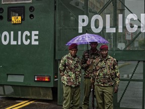 Kenyan police stand under the rain by a barrier blocking off vehicle and pedestrian access, amid tight security outside the Supreme Court in downtown Nairobi, Kenya Tuesday, Nov. 14, 2017. The Supreme Court is due to hear petitions challenging President Uhuru Kenyatta's re-election in October's repeat presidential poll, after it previously had nullified Kenyatta's August reelection citing irregularities and illegalities. (AP Photo/Ben Curtis)