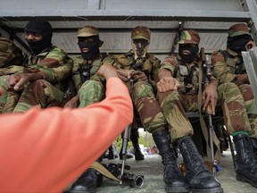 Zimbabwean soldiers bump fists with joyful protesters thanking them near Zimbabwe Grounds in Harare, Zimbabwe Saturday, Nov. 18, 2017. Opponents of Mugabe are demonstrating for the ouster of the 93-year-old leader who is virtually powerless and deserted by most of his allies. Writing in Shona on poster refers to Mugabe in a respectful way saying "Go and rest now". (AP Photo/Ben Curtis)