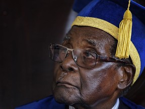 Zimbabwe's President Robert Mugabe sits for formal photographs with university officials, after presiding over a student graduation ceremony at Zimbabwe Open University on the outskirts of Harare, Zimbabwe Friday, Nov. 17, 2017. Mugabe is making his first public appearance since the military put him under house arrest earlier this week. (AP Photo/Ben Curtis)