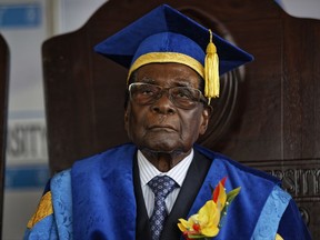 Zimbabwe's President Robert Mugabe sits for formal photographs with university officials, after presiding over a student graduation ceremony at Zimbabwe Open University on the outskirts of Harare, Zimbabwe Friday, Nov. 17, 2017. Mugabe made his first public appearance since the military put him under house arrest earlier this week. (AP Photo/Ben Curtis)