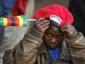 A young supporters of Zimbabwe's President in waiting Emmerson Mnangagwa adjusts his beret as he awaits his arrival at the Zanu-PF party headquarters in Harare, Zimbabwe Wednesday, Nov. 22, 2017. Mnangagwa has emerged from hiding and returned home ahead of his swearing-in Friday. Crowds have gathered at the ruling party's headquarters for his first public remarks. Mnangagwa will replace Robert Mugabe, who resigned after 37 years in power when the military and ruling party turned on him for firing Mnangagwa and positioning his wife to take power. (AP Photo/Ben Curtis)