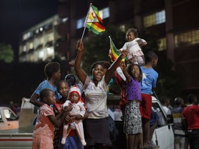 Zimbabweans celebrate at night at an intersection in downtown Harare, Zimbabwe Tuesday, Nov. 21, 2017. Mugabe resigned as president with immediate effect Tuesday after 37 years in power, shortly after parliament began impeachment proceedings against him. (AP Photo/Ben Curtis)