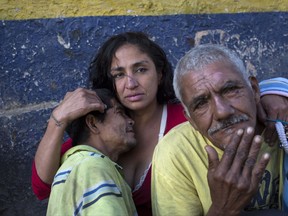 A homeless woman named Jenny embraces her friends Jose Alonso, 40, left, and Rafael Santos, 62, in downtown Tegucigalpa, Honduras, Thursday, Nov. 23, 2017. General elections will be held nationwide on Sunday. (AP Photo/Rodrigo Abd)