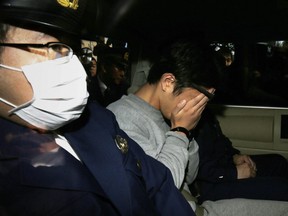 Suspect Takahiro Shiraishi (C) covers his face with his hands as he is transported to the prosecutor's office from a police station in Tokyo on November 1, 2017.  The 27-year-old Japanese man, who was arrested after police found nine dismembered corpses rotting in his house, has confessed to killing all his victims over a two-month spree after contacting them via Twitter, media reports.