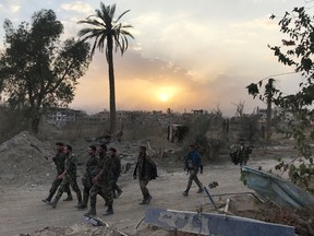 Syrian government forces walk through a road in a northeastern district of Deir Ezzor on November 5, 2017, after retaking the city from ISIL.