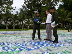 This handout picture released by Colombia's Presidency shows President Juan Manuel Santos listening to a member of the anti-narcotics police as he walks over 12 ton of cocaine on November 8, 2017 in Apartado, Antioquia, Colombia. Santos announced Colombia's police had seized 12 tons of cocaine, which he said was the largest single drug seizure in the history of the country.