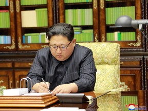 This photo taken on November 28, 2017 and released on November 29, 2017 by North Korea's official Korean Central News Agency (KCNA) shows North Korean leader Kim Jong-Un signing an order document of a test-fire of the inter-continental ballistic rocket Hwasong-15.