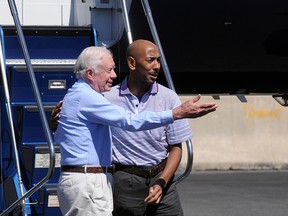 Former U.S. President Jimmy Carter steps off a plane with Aijalon Mahli Gomes on August 27, 2010 at Logan International Airport in Boston, Massachusetts. Gomes, held in custody in North Korea after crossing into the country illegally since January, was released at the behest of Carter.