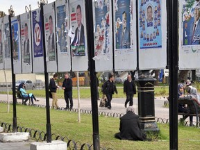 People stroll by electoral posters for the local elections, Wednesday, Nov.22, 2017 in Algiers. Algeria votes Thursday to renew local assemblies. (AP Photo/Anis Belghoul)