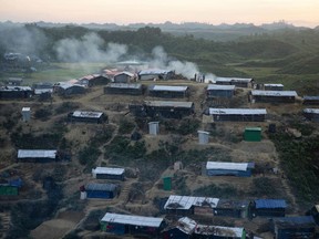 Rohingya Muslims stand, as smoke emits from the Hakim Para refugee camp in Ukhiya, Bangladesh Monday, Nov. 13, 2017. More than 600,000 members of the Muslim minority have fled to Bangladesh since August, when Rohingya insurgents attacked Myanmar police and paramilitary posts, and security forces responded with a scorched-earth campaign against Rohingya villages. (AP Photo/A.M. Ahad)