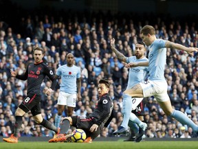 Manchester City's John Stones, right and Arsenal's Mesut Ozil centre, vie for the ball, during the English Premier League soccer match between Manchester City and Arsenal, at the Etihad Stadium, in Manchester, Sunday, Nov. 5, 2017. (Martin Rickett/PA via AP)