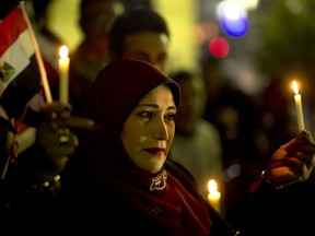 A woman holds candles and a national flag during a candlelight vigil for victims of a Friday mosque attack at the Journalists Syndicate, in Cairo, Egypt, Monday, Nov. 27, 2017. Friday's assault was Egypt's deadliest attack by Islamic extremists in the country's modern history, a grim milestone in a long-running fight against an insurgency led by a local affiliate of the Islamic State group.(AP Photo/Amr Nabil)