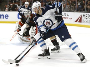 Winnipeg Jets right wing Joel Armia (40) controls the puck with Anaheim Ducks center Logan Shaw (48) and goalie John Gibson (36) defending during the first period of an NHL hockey game in Anaheim, Calif., Friday, Nov. 24, 2017. (AP Photo/Alex Gallardo)