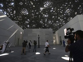 In this Monday, Nov. 6, 2017, photo, members of the media walk around the sculptures in the Louvre Abu Dhabi in Abu Dhabi, United Arab Emirates. The Louvre Abu Dhabi is preparing its grand opening, unveiling its treasures to the world after a decade-long wait and questions over laborers' rights. The museum, which opens on Saturday, Nov. 11 to the public, encompasses work from both the East and West. (AP Photo/Kamran Jebreili)