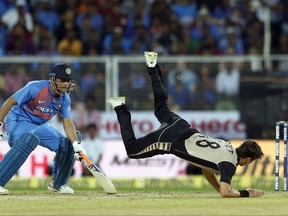 India's Mahendra Singh Dhoni, left, watches New Zealand's Trent Boult, right, dive to stop the ball during their third Twenty20 international cricket match in Thiruvananthapuram, India, Tuesday, Nov. 7, 2017. (AP Photo/Aijaz Rahi)