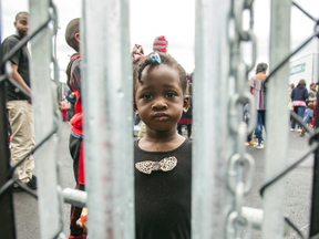 A girl who crossed the U.S. border into Canada illegally with her family, claiming refugee status, looks through a fence at a temporary detention centre in Blackpool, Quebec, in August.